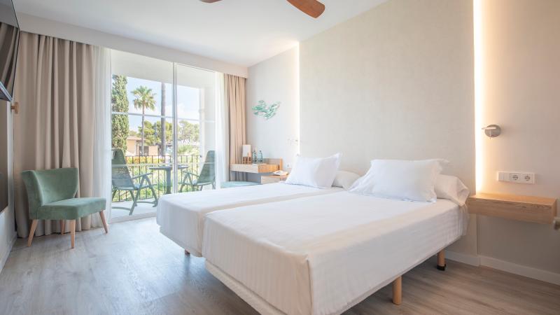 Tr�ningsresor, Ljust hotellrum i Col�nia de Sant Jordi med tv� s�ngar och balkong mot gr�nska.