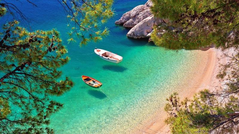 Tr�ningsresor, Strandvik i Brela med turkost vatten, sm� b�tar och klippor i natursk�n milj�.